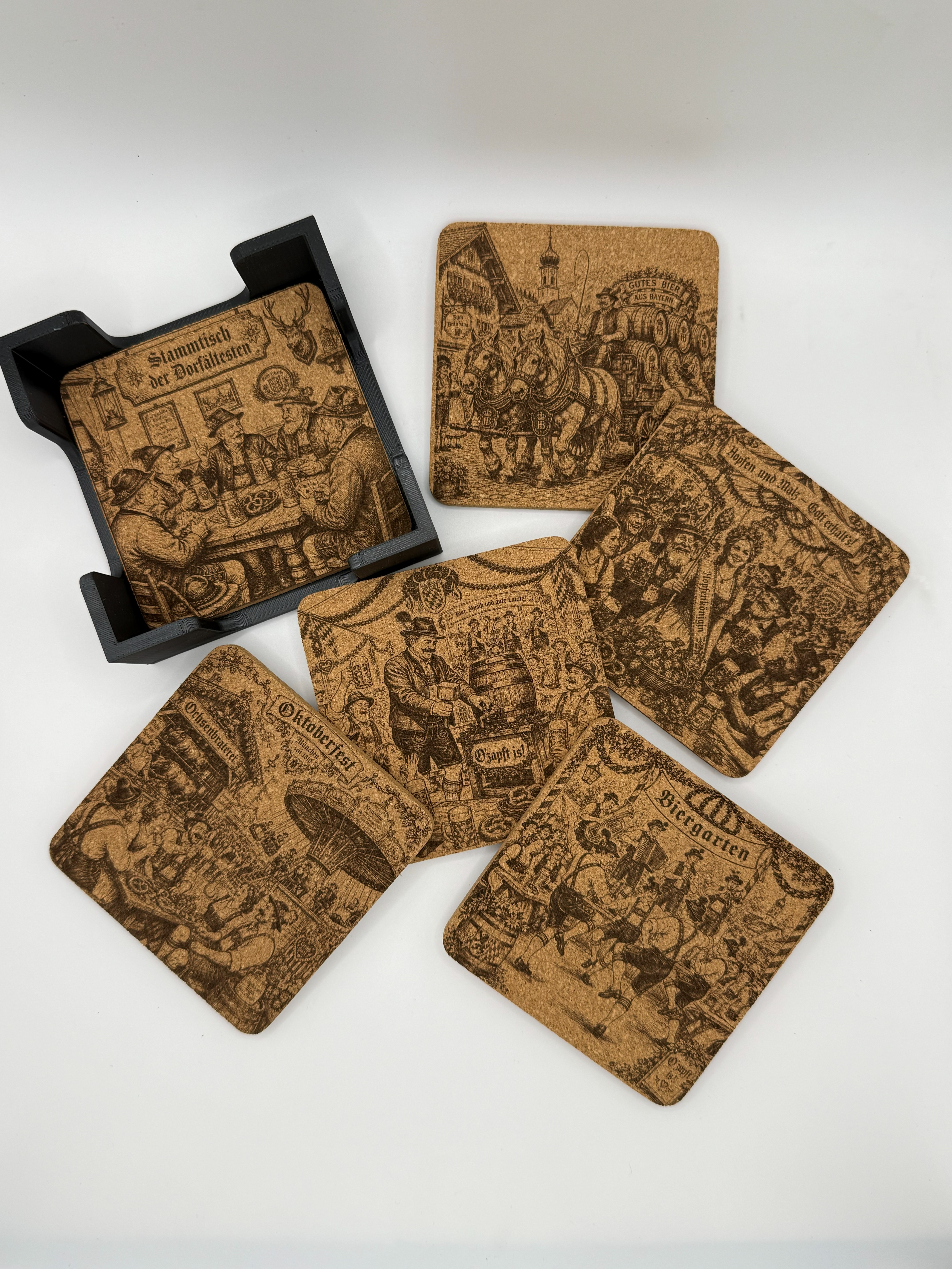 Sechs Korkbierdeckel des Sets Teil 2 mit unterschiedlichen bayrischen Motiven, ausgebreitet neben dem Halter